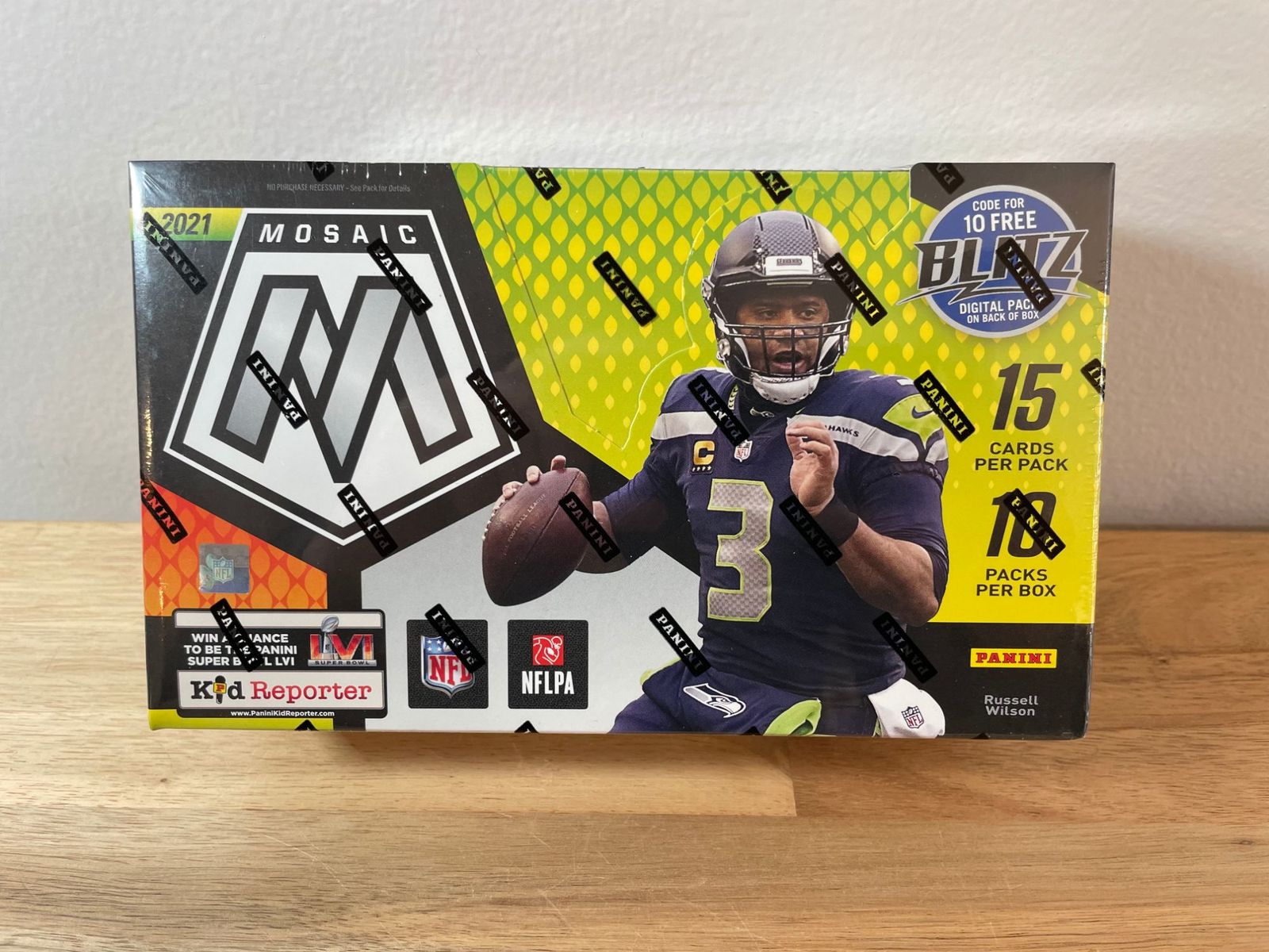 A sealed 2021 Panini Mosaic Football hobby box, 10 packs of 15 cards, on a wooden shelf
